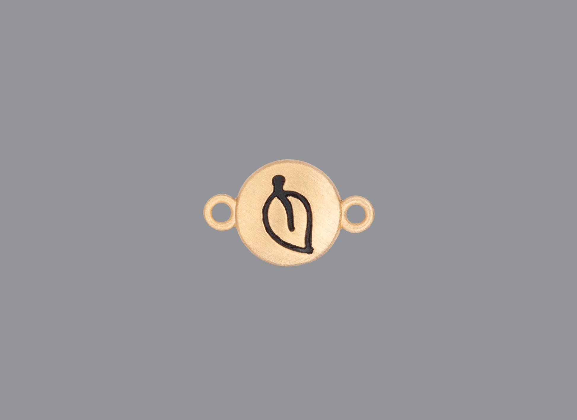Round emoji connector in gold with a leaf engraving on gray background