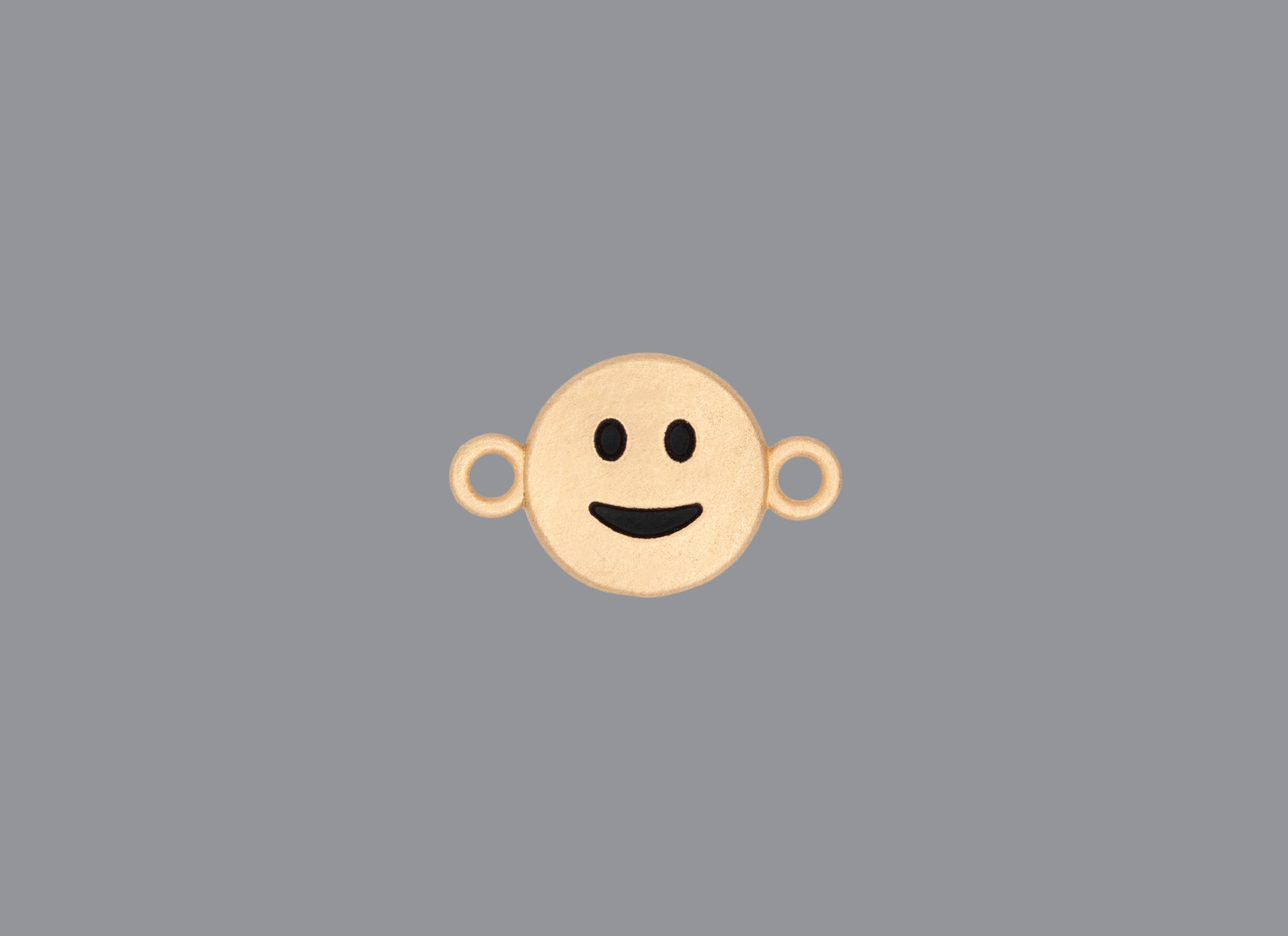 Round emoji connector in gold with a smile engraving on gray background