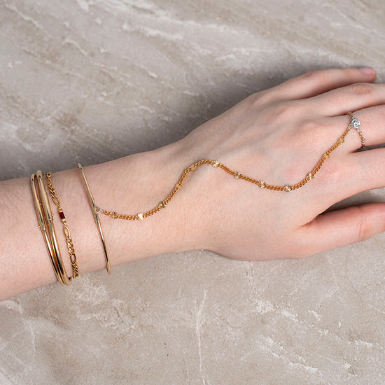 Hand wearing gold bracelets and a ring permanent bangle Riva Precision