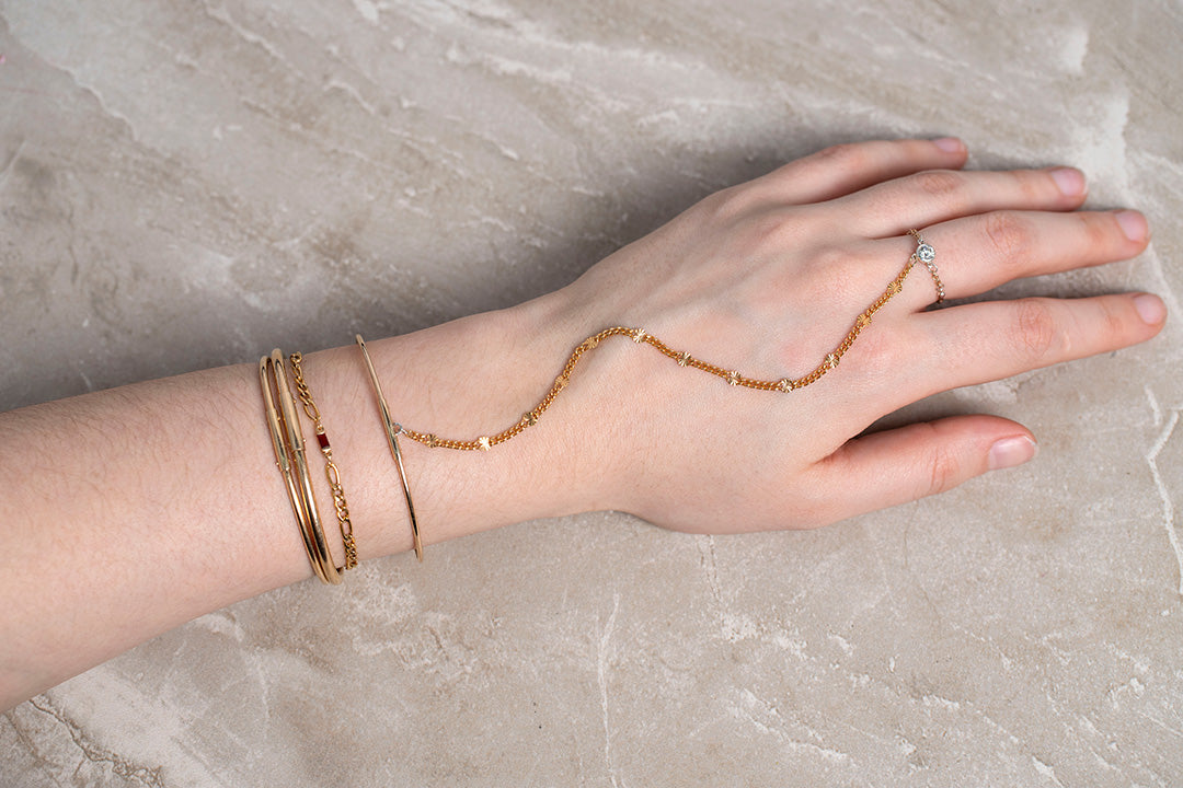 Hand wearing gold bracelets and a ring permanent bangle Riva Precision