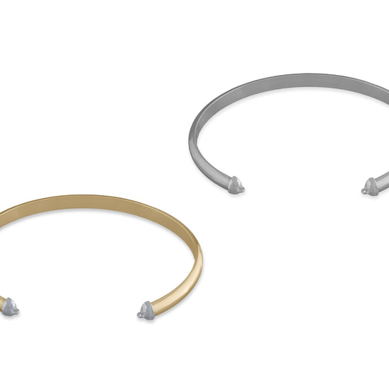 Two cuffs made from half-round wire, one in silver and one in gold color, with caps on the ends.