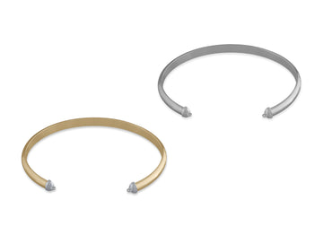 Two cuffs made from half-round wire, one in silver and one in gold color, with caps on the ends.