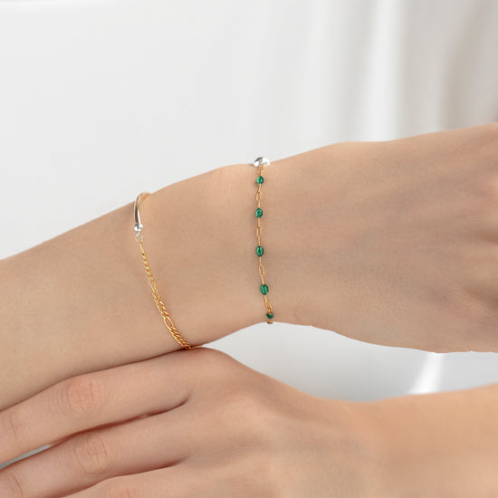 Two bracelets on a wrist against a white background