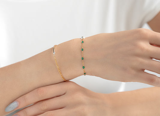 Two bracelets on a wrist against a white background