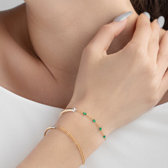 Close-up of a person wearing two gold bracelets on a white background