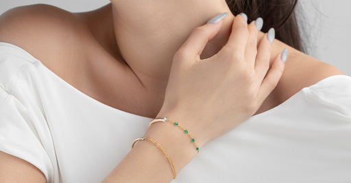 Close-up of a person wearing two gold bracelets on a white background