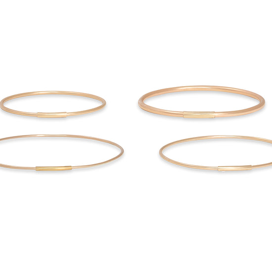 Four gold bangles on a white background
