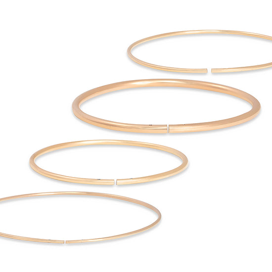 Set of gold permanent bangles on a white background