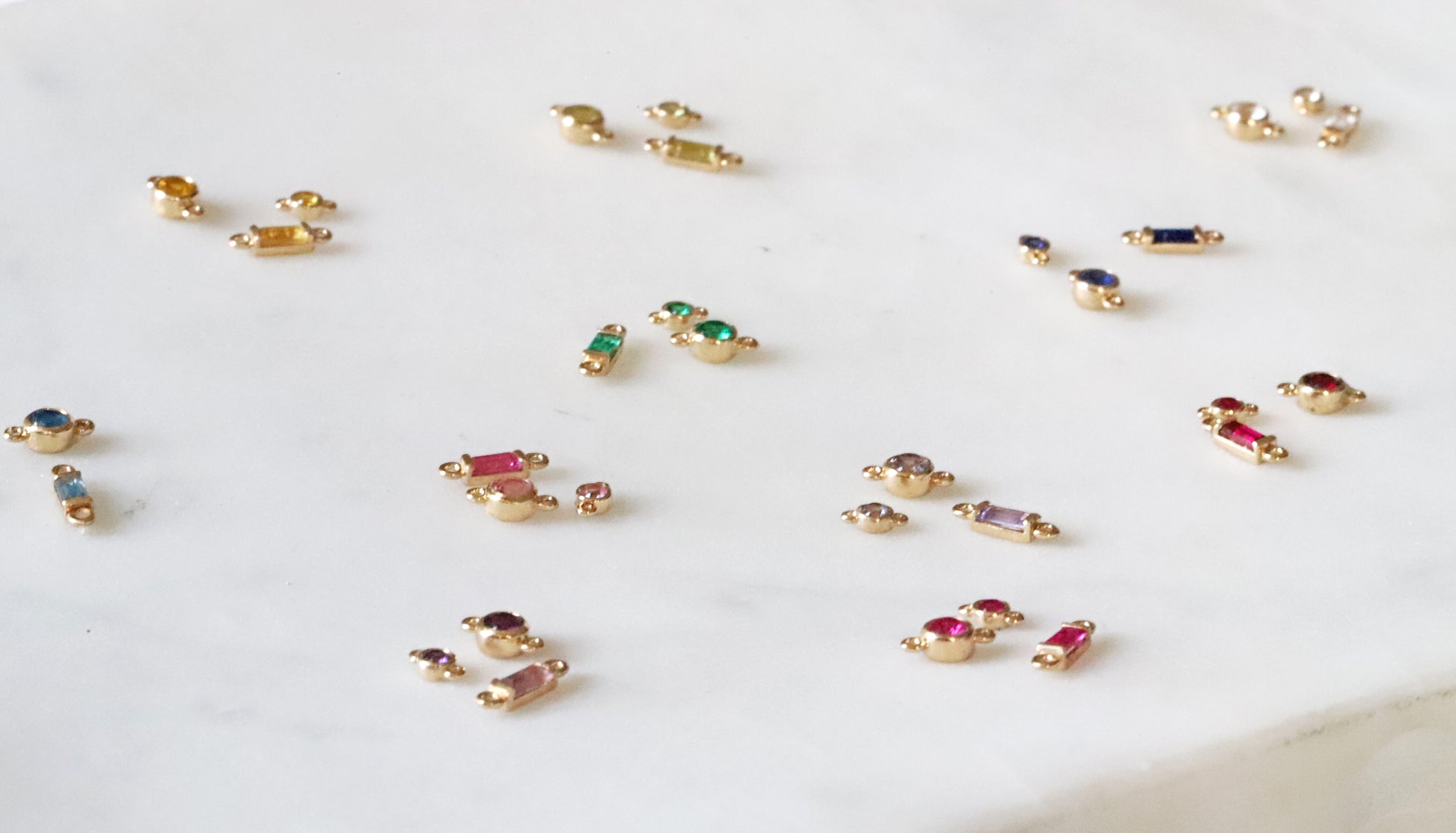 Small gold jewelry pieces with gemstones on a white surface