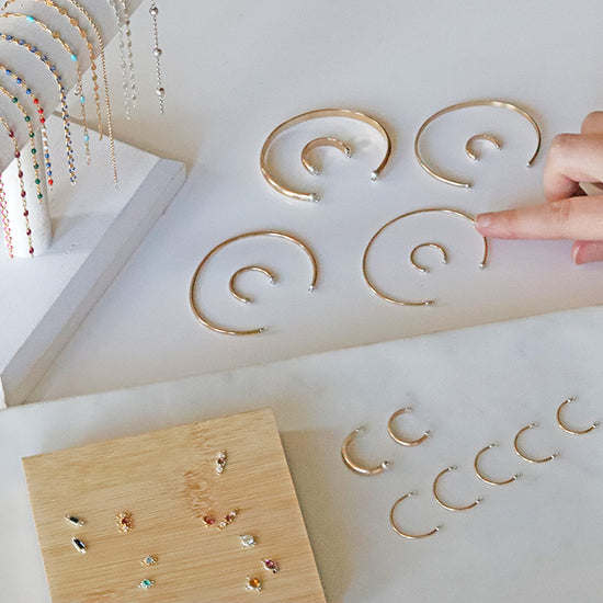 GoldCuff Rings displayed on a white surface with a hand reaching out to pick one up.
