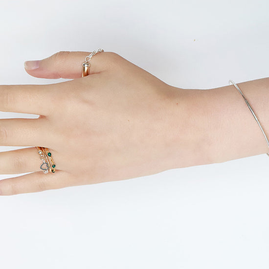 Hand wearing multiple rings on a white background