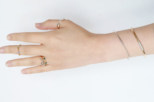 Hand wearing multiple rings on a white background