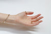 Hand wearing gold rings and a bracelet on a light background