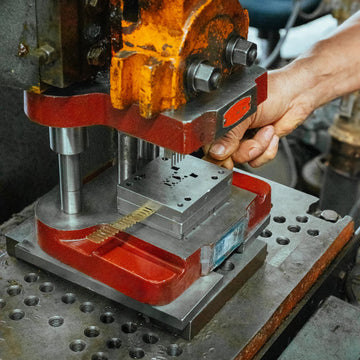 Person operating a metalworking machine with a focus on the equipment and hand.