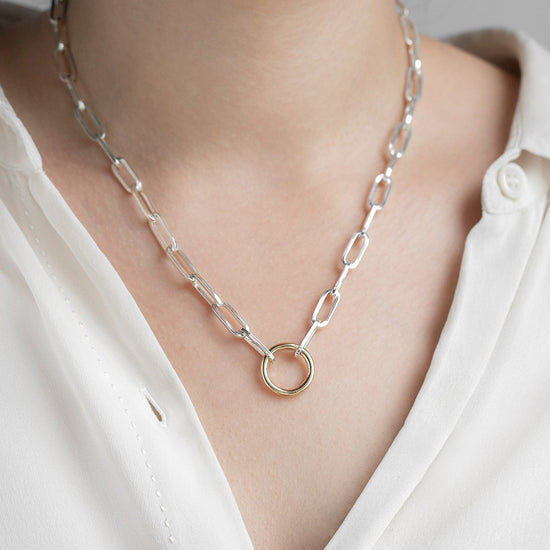 Silver chain necklace with a gold invisible clasp worn by a person in a white shirt.