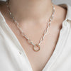 Silver chain necklace with a gold invisible clasp worn by a person in a white shirt.