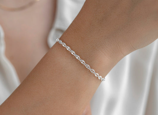 Silver chain on a wrist with a plain background
