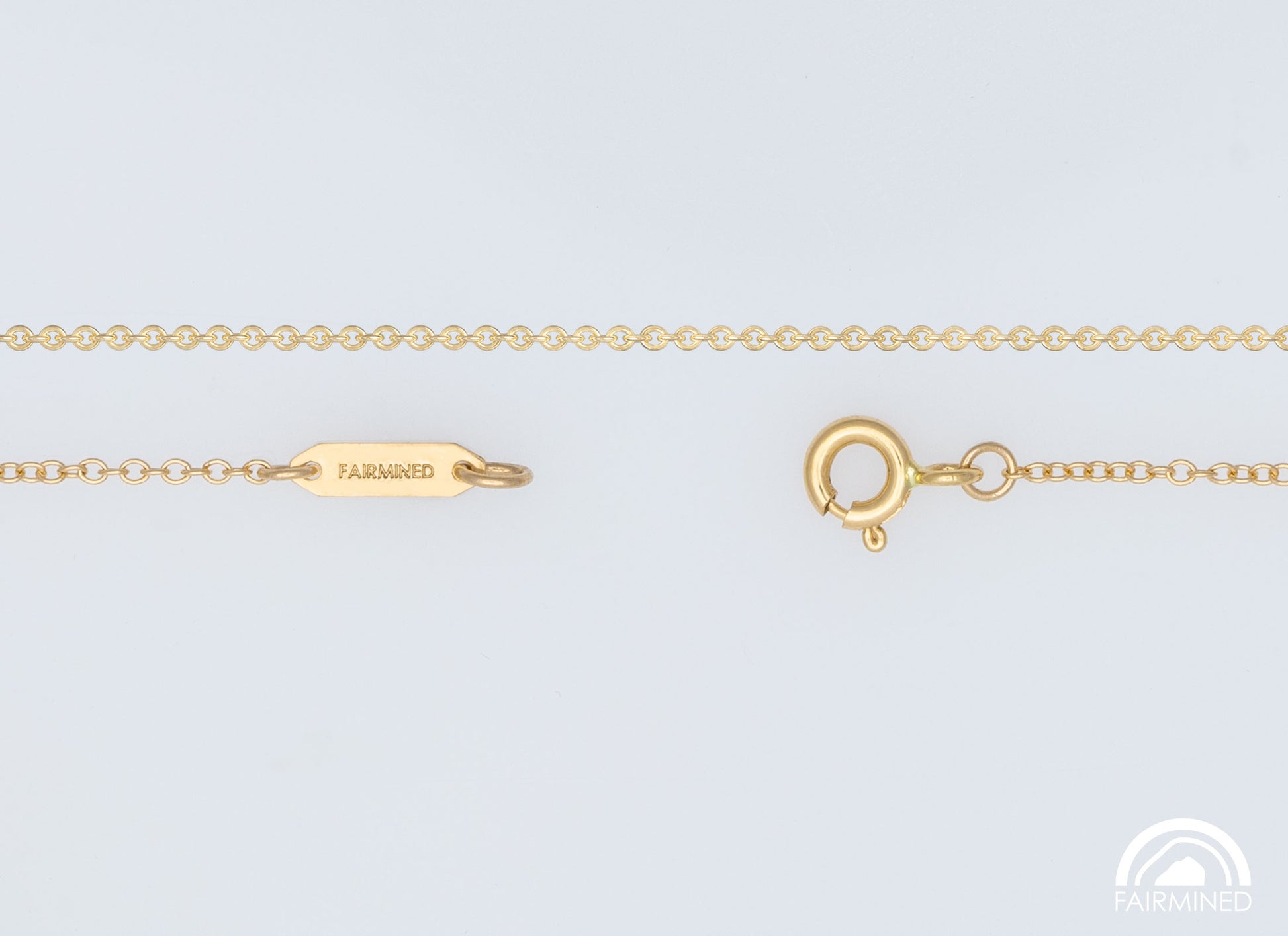 A fairmined gold cable chain necklace with a spring ring clasp and jump rings, laid out on a white background.