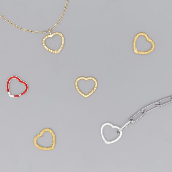 A series of heart-shaped invisible clasps in gold, silver, and red colors placed on a chain necklace.