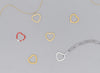 A series of heart-shaped invisible clasps in gold, silver, and red colors placed on a chain necklace.