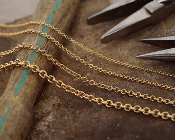 Gold chains on a wooden surface with pliers