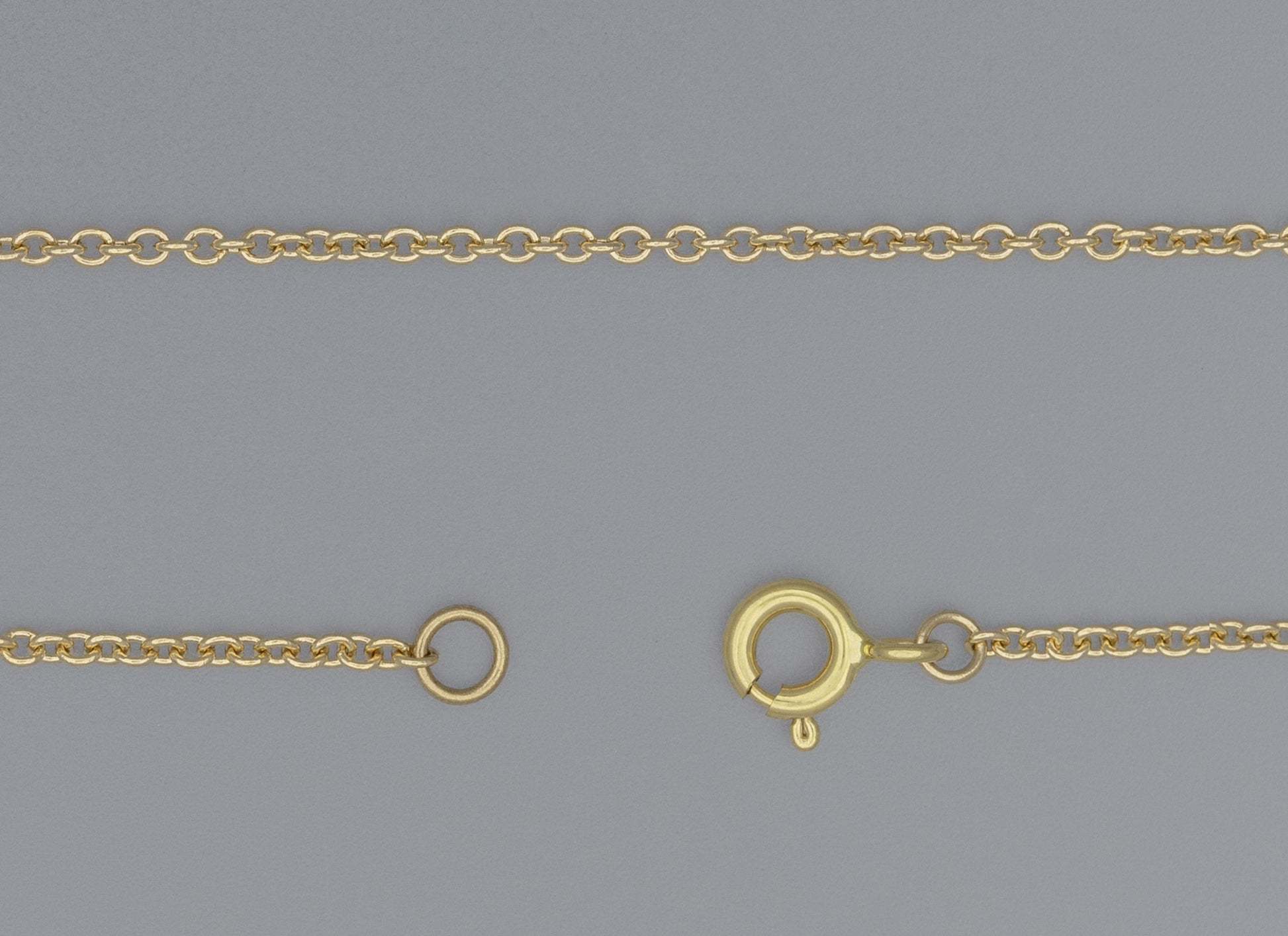 A close-up image of a gold cable chain necklace with a focus on the extra-small circular links and the clasp.
