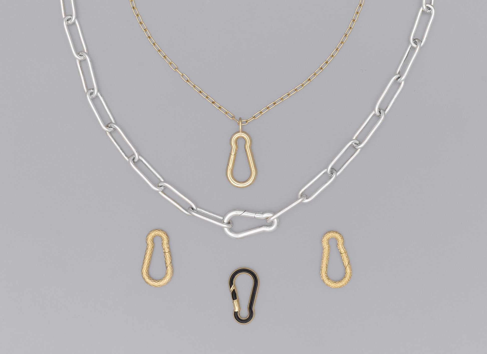A series of carabiner-shaped invisible clasps in gold and silver colors, attached to a chain necklace.