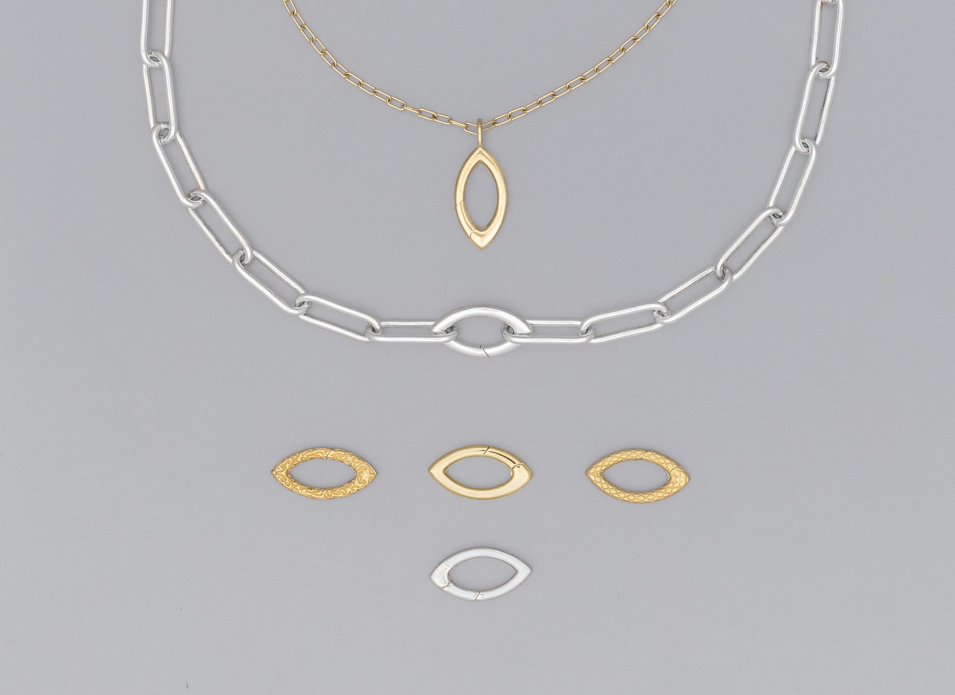 A collection of jewelry components, including a silver and gold-colored clasp with a marquise shape, and two arcs with incognito hinges.