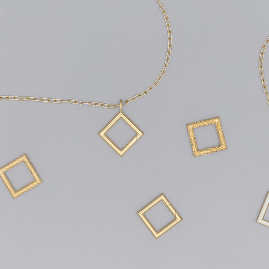 A collection of square-shaped invisible clasps in various metallic finishes arranged on a surface with chain links.