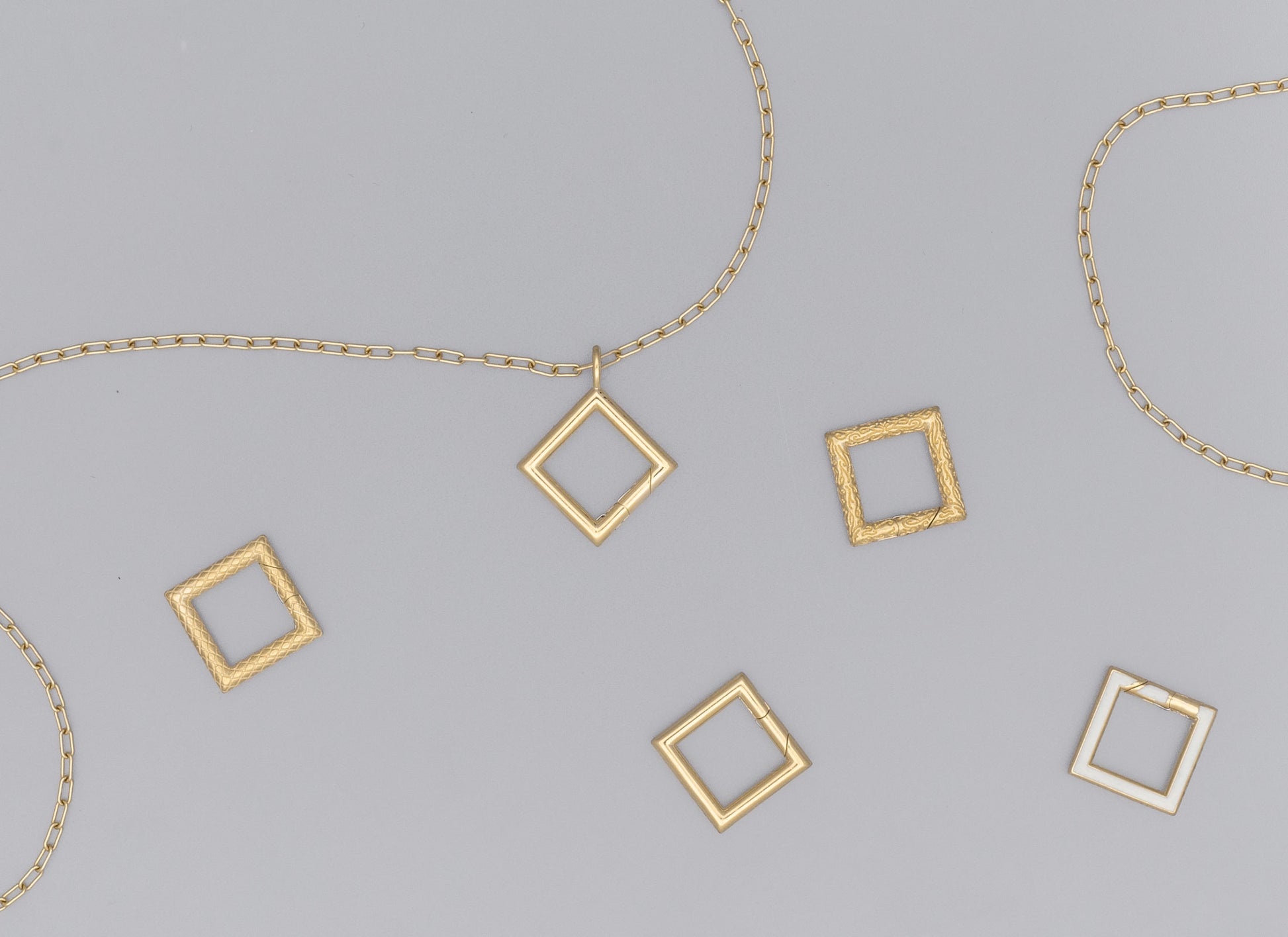 A collection of square-shaped invisible clasps in various metallic finishes arranged on a surface with chain links.