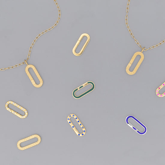 A collection of flat paper clip-shaped invisible clasps in various colors including gold, silver, green, pink, and blue, displayed on a grey background.