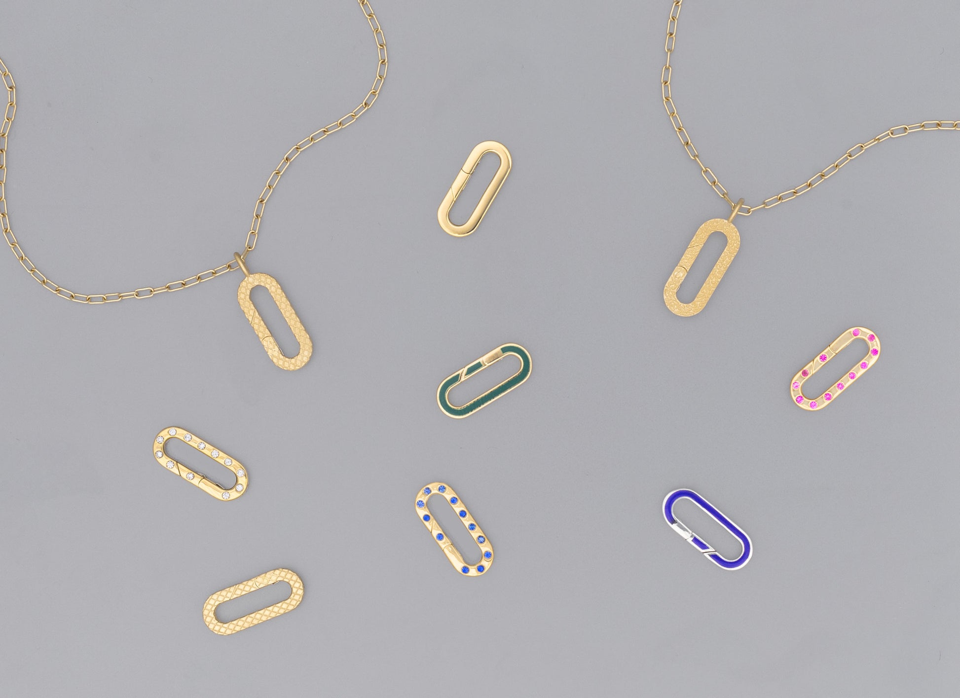 A collection of flat paper clip-shaped invisible clasps in various colors including gold, silver, green, pink, and blue, displayed on a grey background.