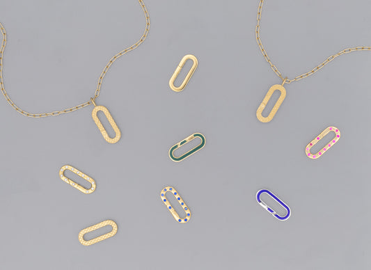A collection of flat paper clip-shaped invisible clasps in various colors including gold, silver, green, pink, and blue, displayed on a grey background.