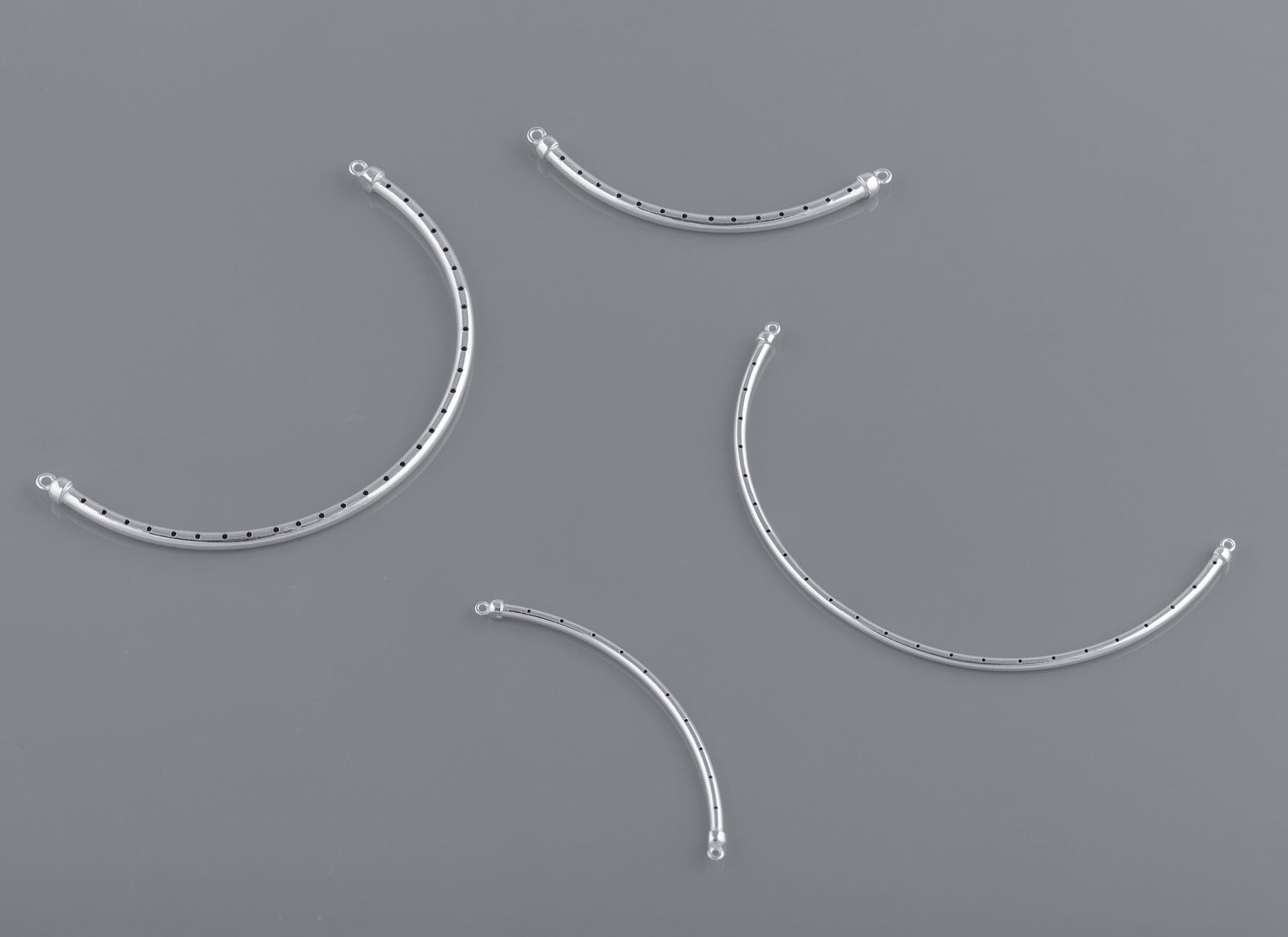A set of curved bangle wires with rivets on a grey background, used for crafting purposes in jewelry making.