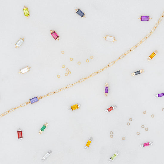 Colorful birthstone connectors and jewelry components on a light gray background