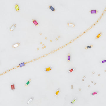 Colorful birthstone connectors and jewelry components on a light gray background