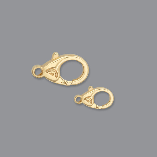 Two sizes of lobster claw clasps made of Fairmined gold, displayed against a grey background.
