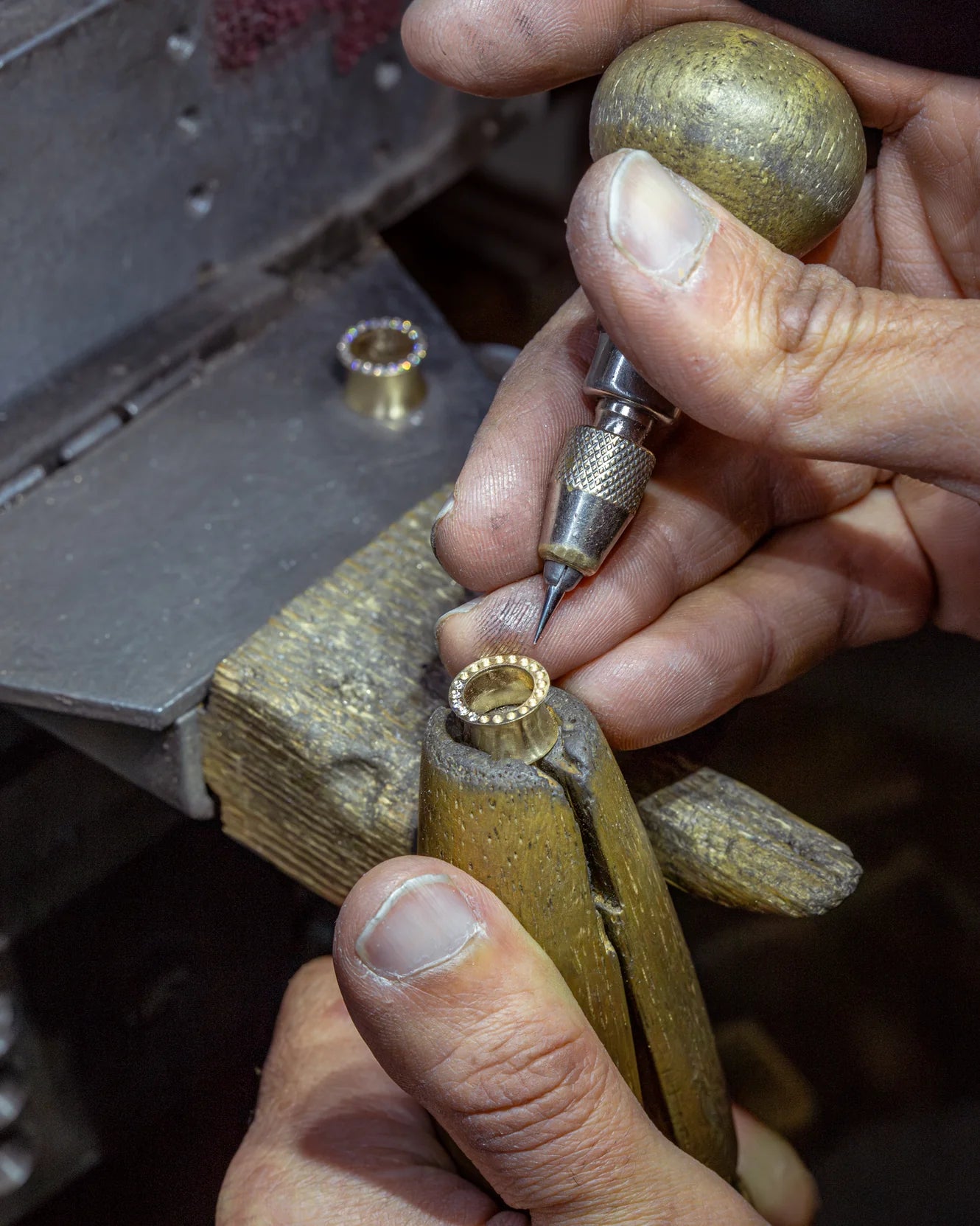 Close-up of hands using a small tool on a wooden object with a metal clamp.