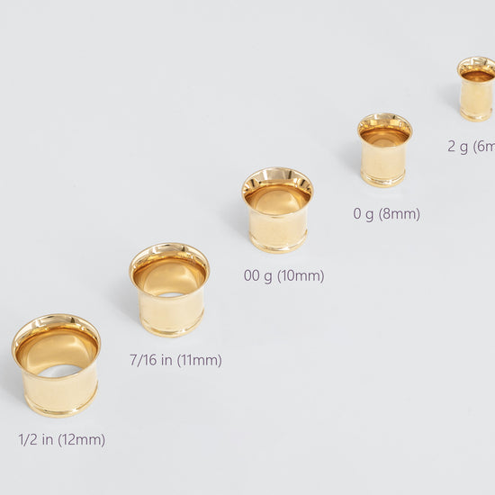 Set of gold gauges with size labels on a light gray background