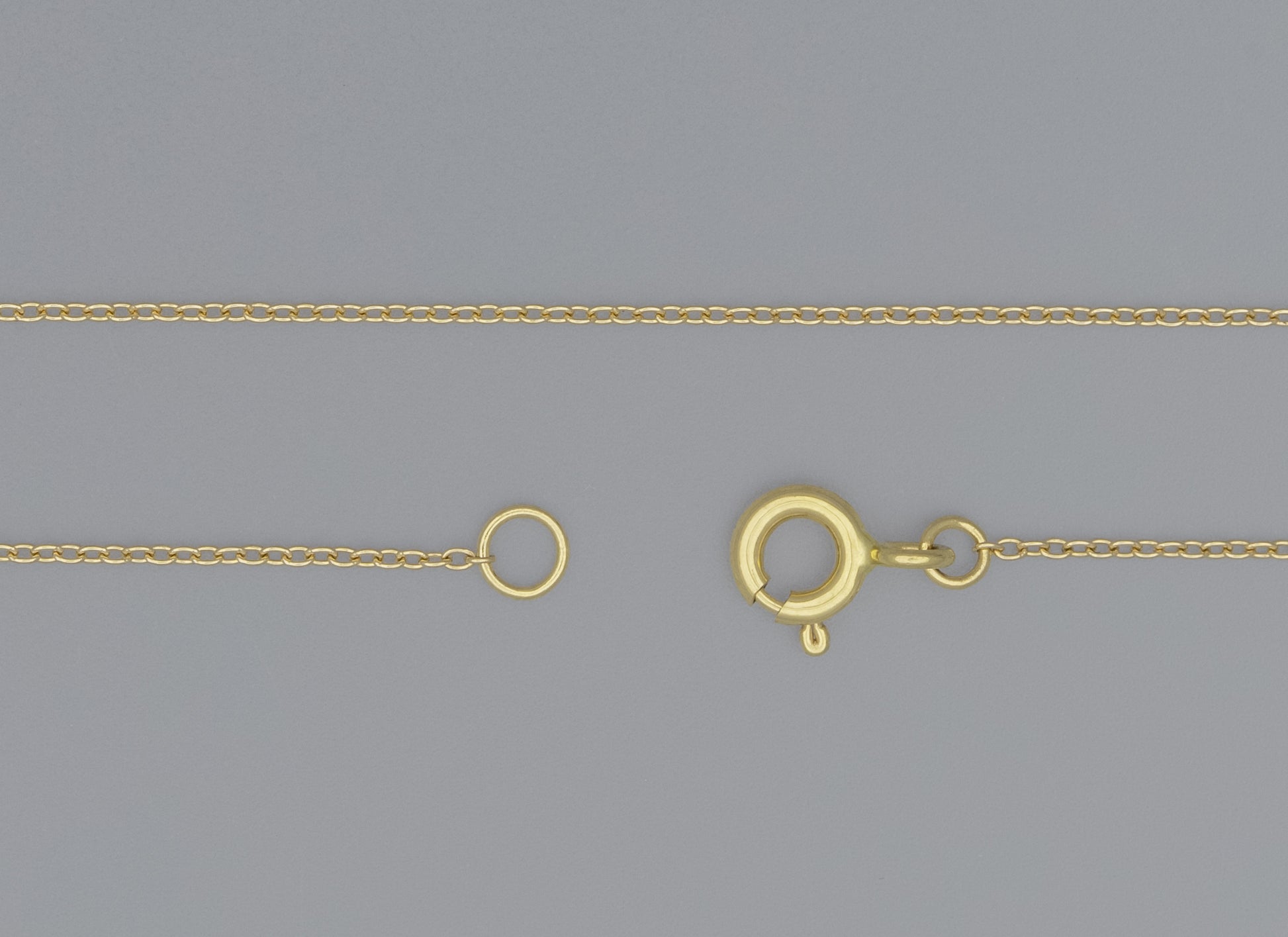 A 0.9mm cable chain necklace with a spring ring clasp and jump rings, displayed on a grey background.