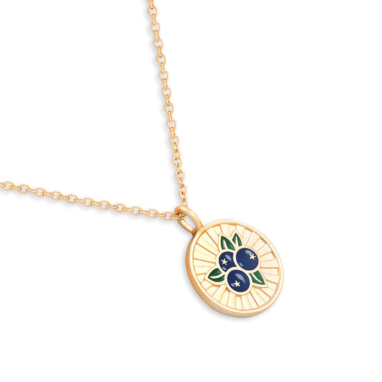 Gold necklace with a circular pendant featuring blueberries on a white background