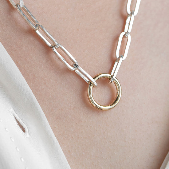 Silver chain necklace with a round invisible clasp on a person's neck.