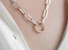 Silver chain necklace with a round invisible clasp on a person's neck.