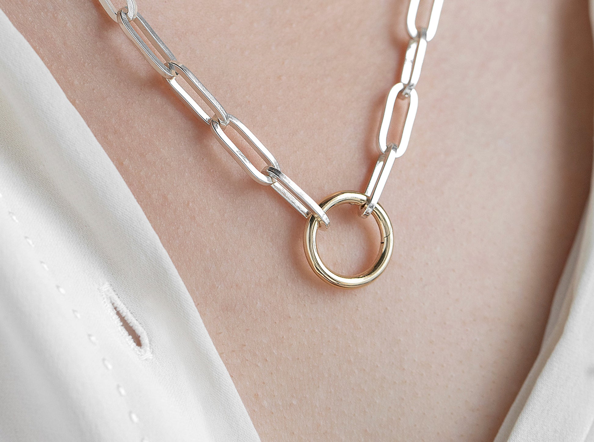 Silver chain necklace with a round invisible clasp on a person's neck.