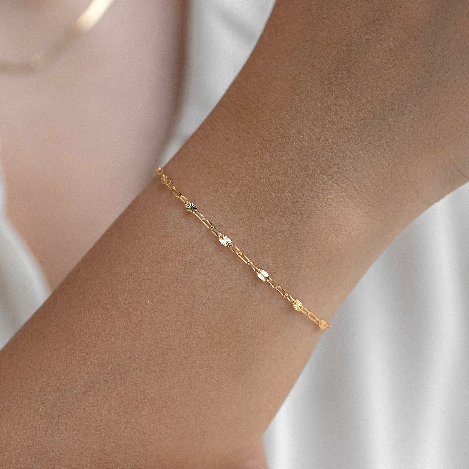 Gold chain on a wrist with a soft white background