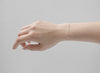 Hand wearing a delicate bracelet on a plain background