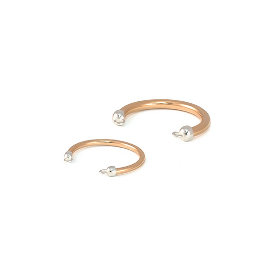 Two gold rings with pearl-like beads on a white background