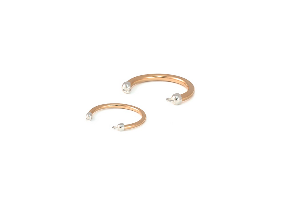 Two gold rings with pearl-like beads on a white background