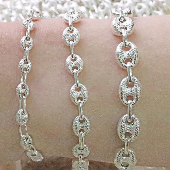 Silver chain mariner bracelet on a wrist with a blurred background