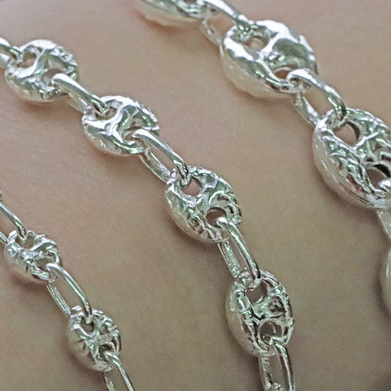 Close-up of a silver chain mariner bracelet on a person's wrist.